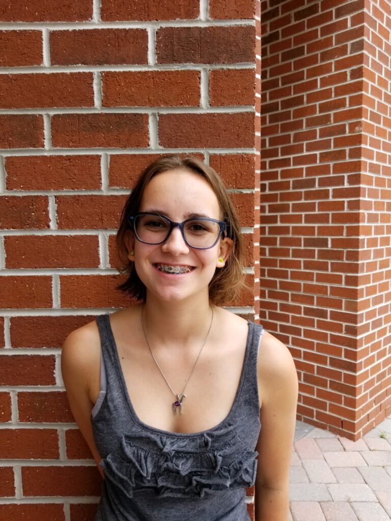 Girl with a bob haircut standing in front of a brick wall