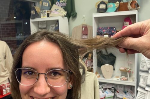 Someone holding part of a woman's hair away from her head to showcase the length.