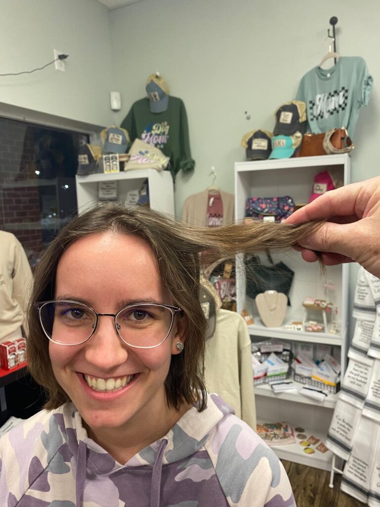 Someone holding part of a woman's hair away from her head to showcase the length.