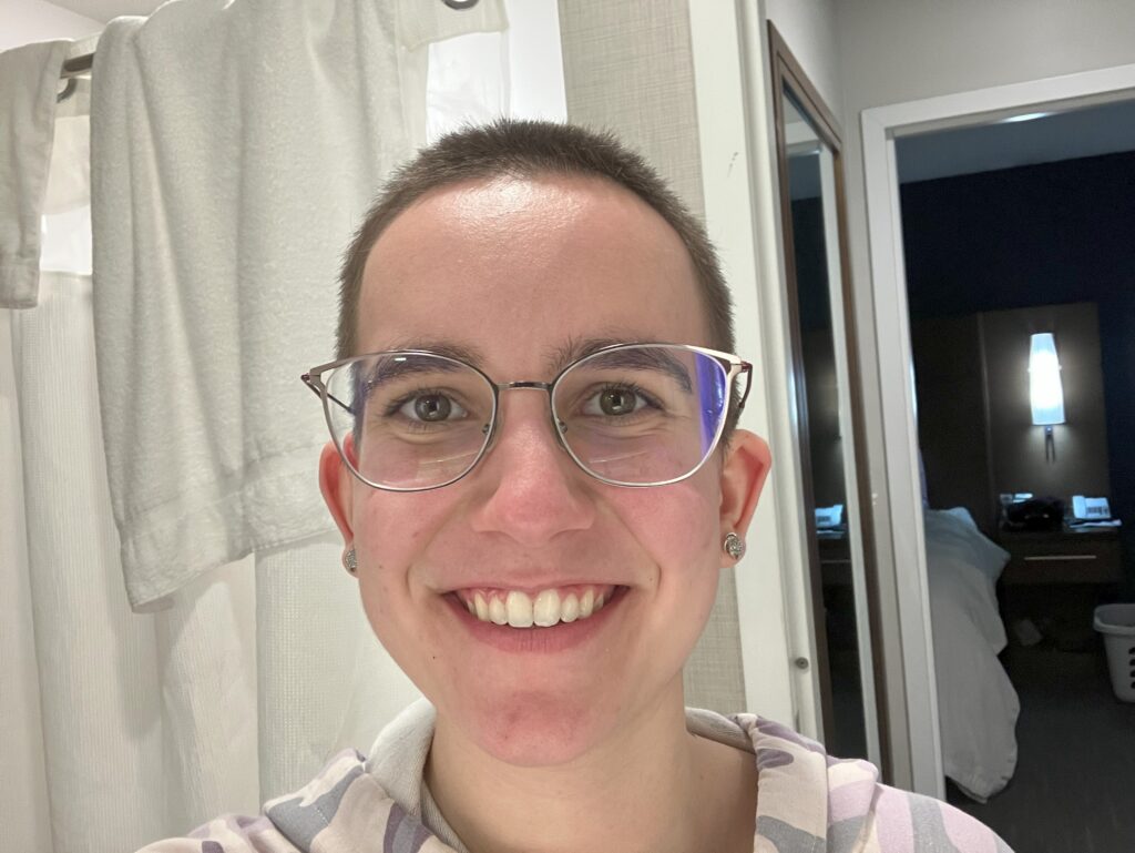 A selfie of smiling woman with a shaved head.