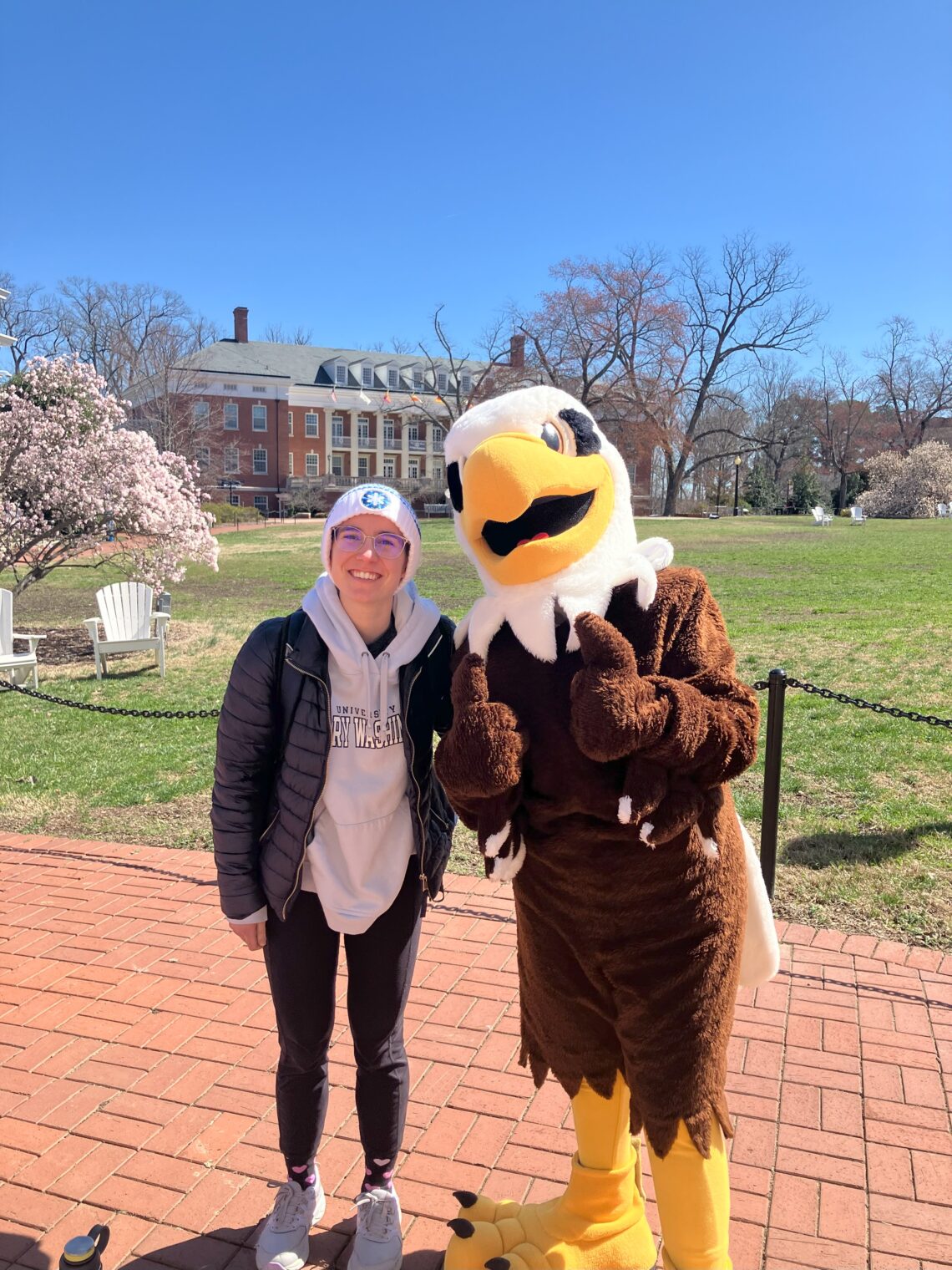 A woman smiling next to an eagle mascot.