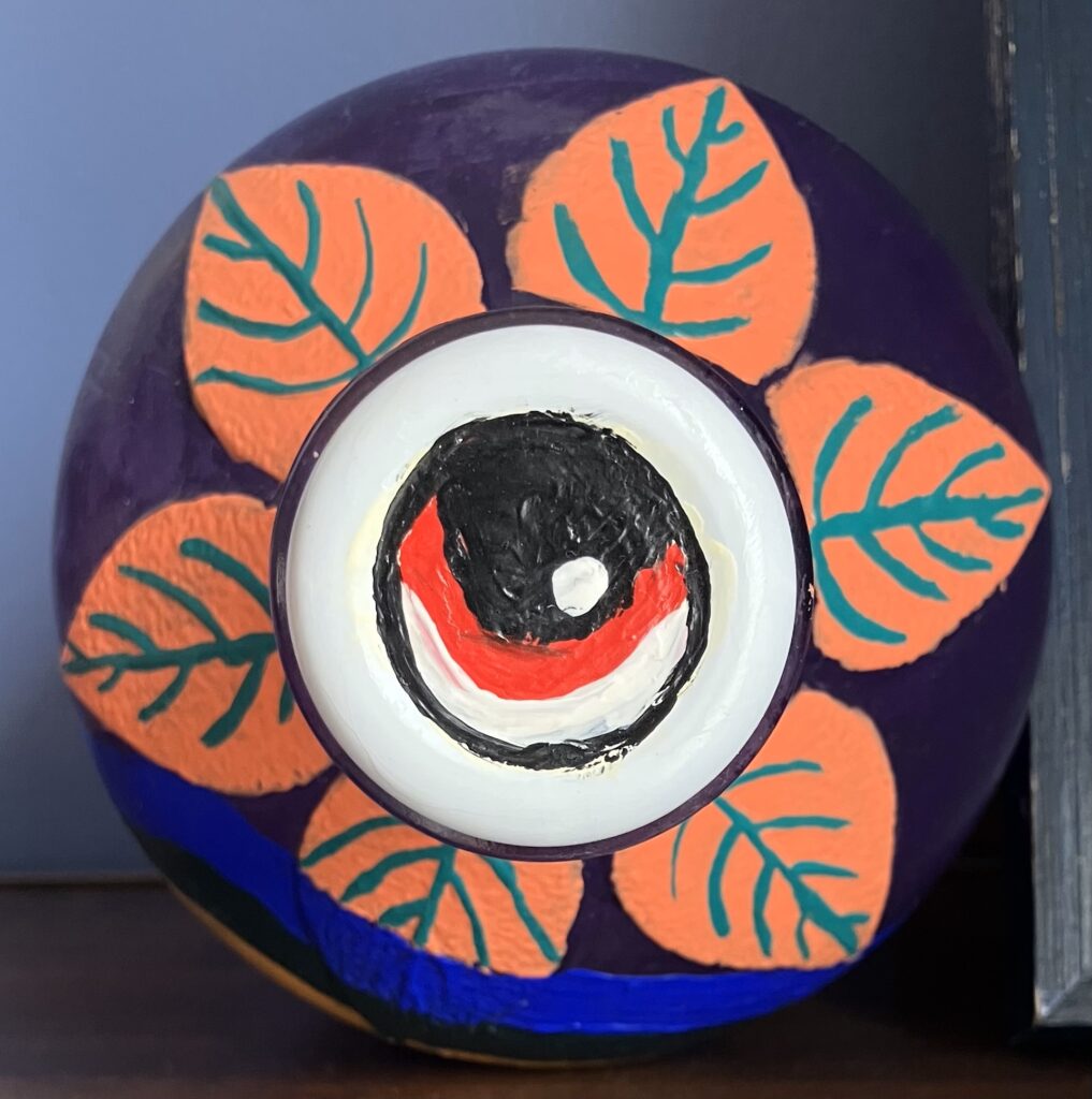 Acrylic paint on an apple cider jar. View of the top of the jar; the cap is painted to look like a red eye, while the neck has pink leaves with green veins.