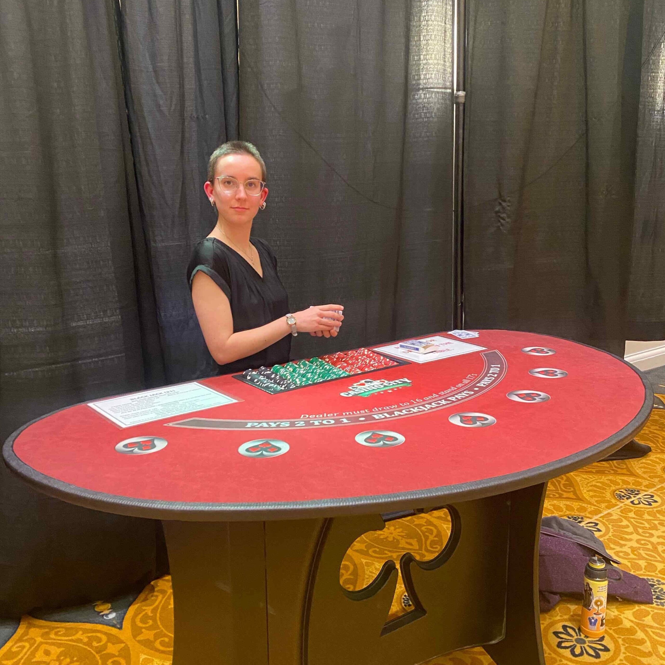 Young woman standing behind a mock casino table.