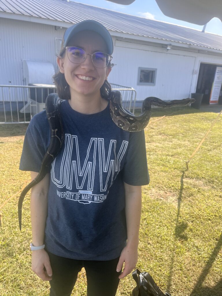 Young woman smiling with a snake on her shoulders.