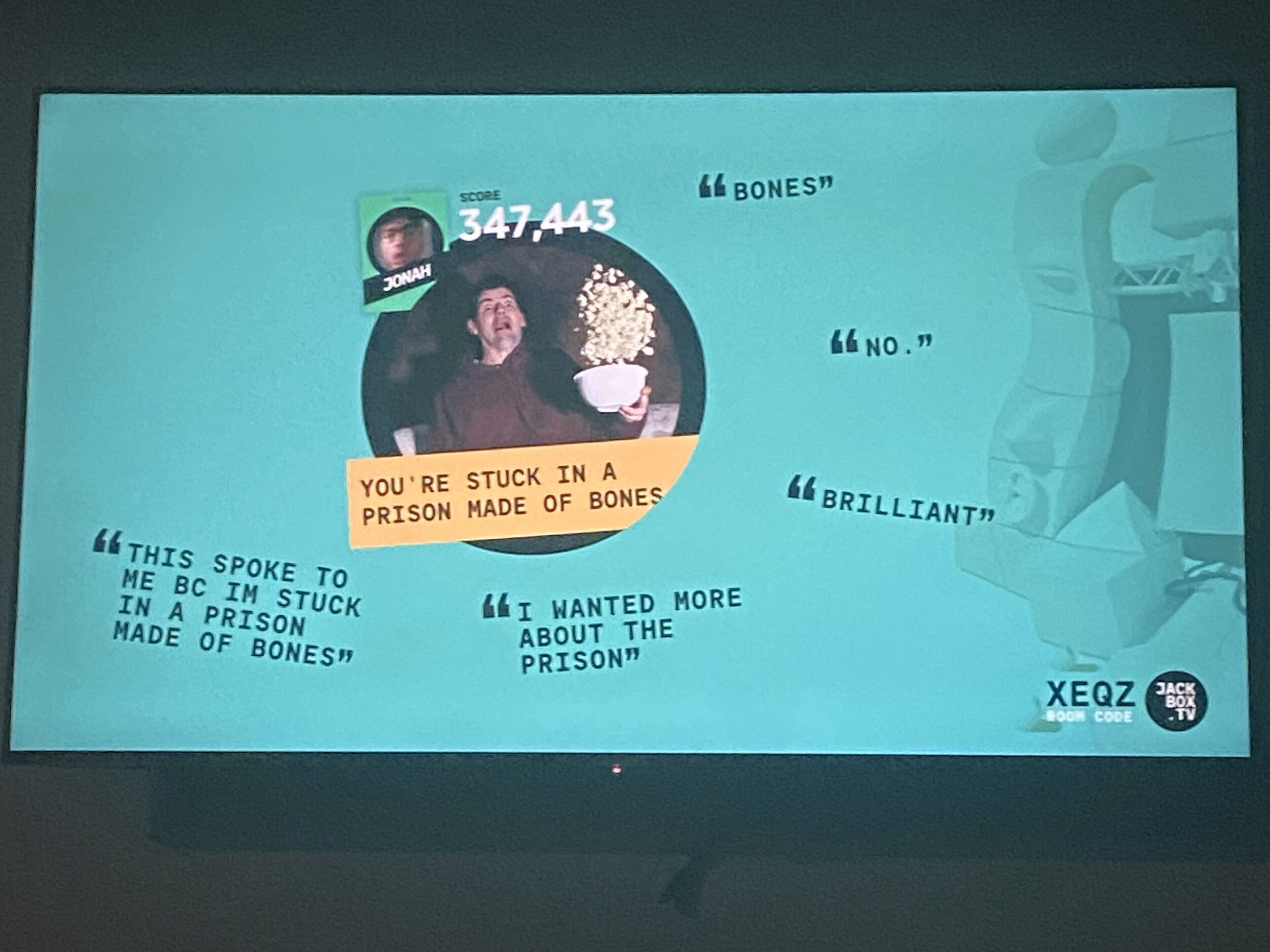 A TV displaying the end of a Jackbox game. The prompt says "You're stuck in a prison made of bones." The reviews are as follows: "No," "Brilliant," "Bones," "I wanted more about the prison," and "This spoke to me because I'm stuck in a prison made of bones."