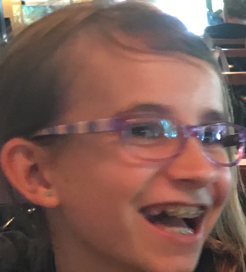 10-year-old Lexi smiling with braces and bangs pushed to the side.