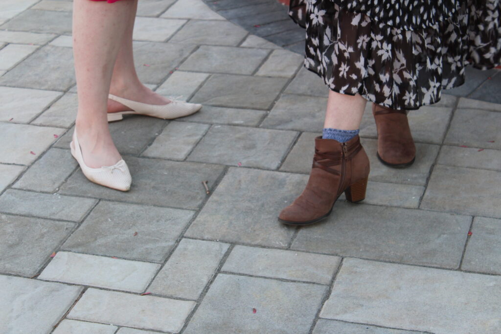 Lexi's and Olivia's dress shoes. Olivia is wearing low, white heels and Lexi wearing brown, heeled ankle boots.