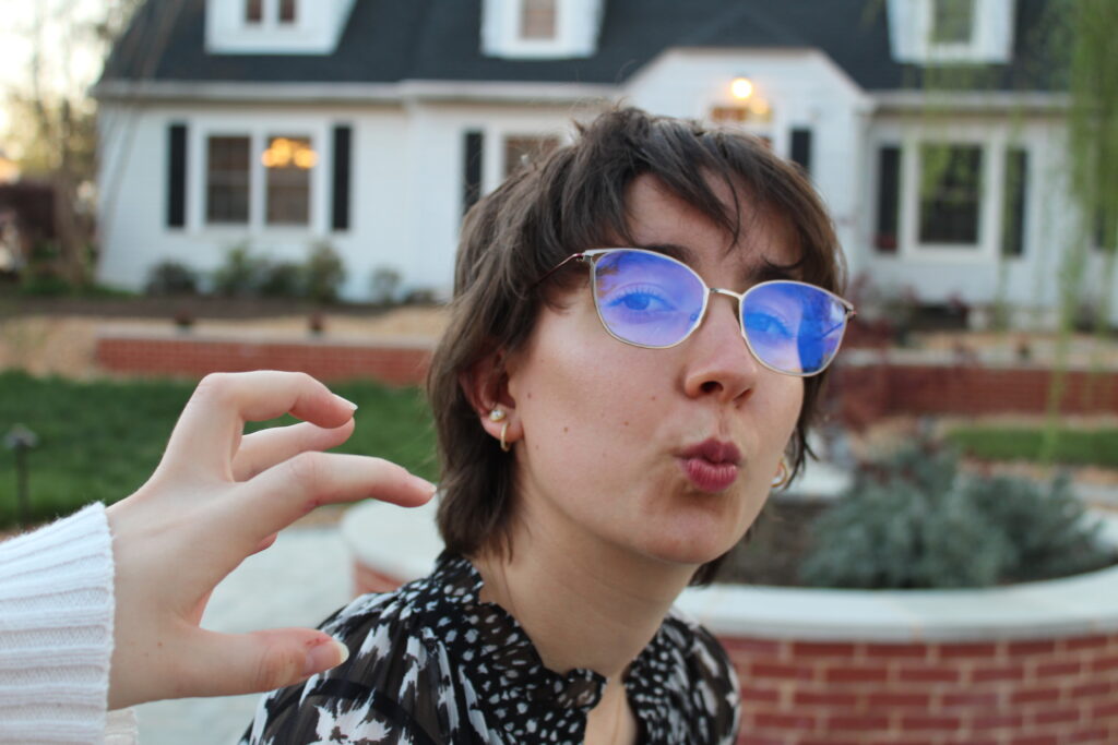 Lexi making a silly face at the camera while Olivia's hand reaches toward her face.