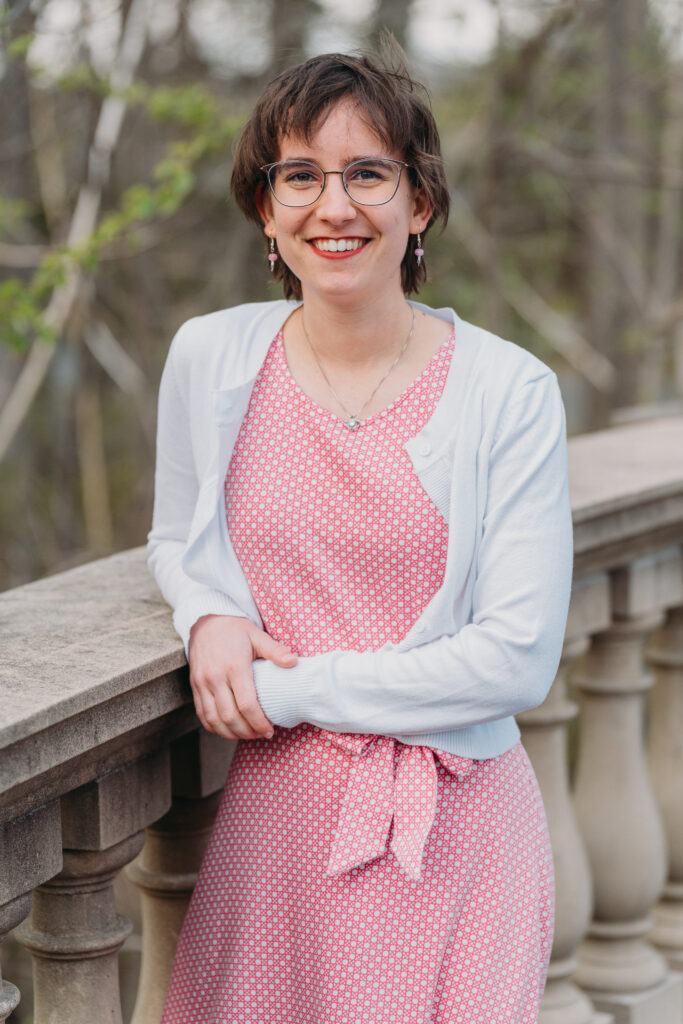 Lexi smiling in a pink dress and white cardigan.