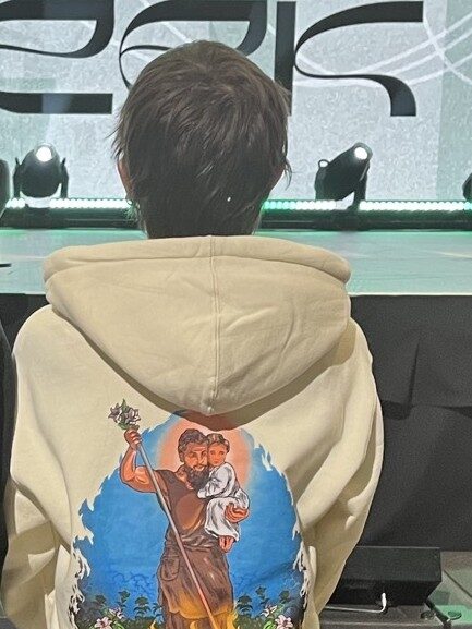 Me facing backward with a hoodie of Saint Joseph holding the Infant Jesus while slaying a horde of demons.